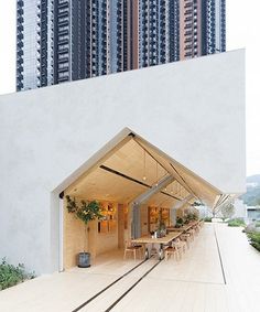 an outdoor dining area with wooden tables and chairs under a tall building in the background