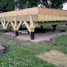 a wooden structure sitting on top of a lush green field