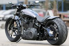 a black motorcycle parked on the street next to a parking lot with cars in the background