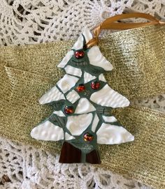 a christmas tree ornament hanging on a lace doily