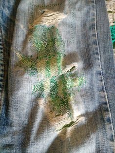 an old pair of jeans with green paint on them