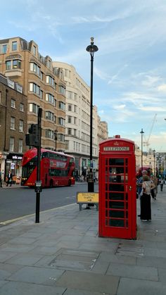 a red phone booth sitting on the side of a road next to a street light