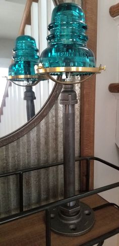 two blue glass lamps sitting on top of a wooden table next to a mirror in a room