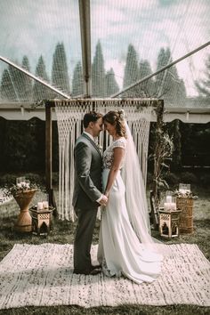 a bride and groom standing in front of a wedding arch