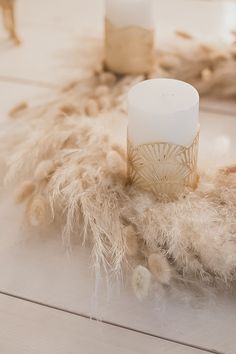 a white candle sitting on top of a wooden table next to some feathers and candles