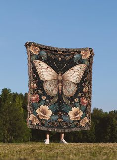 a woman standing in front of a blanket with a large butterfly on it's back