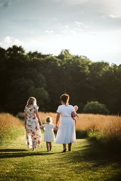 two women and a child are walking in the grass