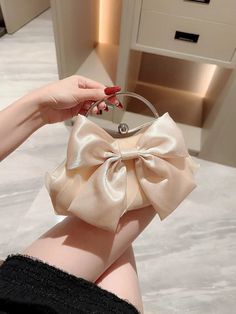 a woman's hand holding a purse with a bow on it