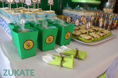 a table topped with green bags filled with food next to cupcakes and cookies