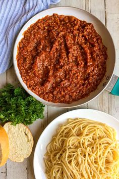 two bowls of spaghetti and bread on a table