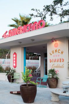 an americano restaurant with large potted plants in front of the entrance and sign