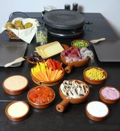 a table topped with bowls filled with different types of food next to an electric skillet