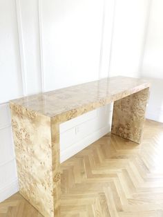 a wooden bench sitting on top of a hard wood floor next to a white wall