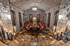 the dining room is set up in an old castle like setting with stone walls and flooring