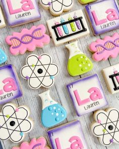 decorated cookies are arranged on a table with letters and symbols in the shape of lab equipment