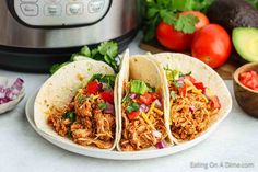 three shredded chicken tacos on a plate next to an instant pot