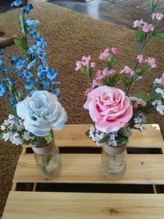 two vases filled with flowers sitting on top of a wooden table next to each other