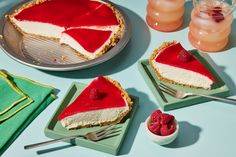 three slices of cheesecake with raspberries on plates next to two cups and spoons