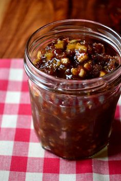 a jar filled with food sitting on top of a red and white checkered table cloth