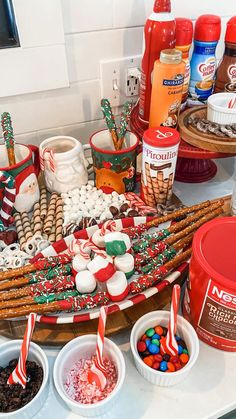 an assortment of candy canes, marshmallows and pretzels on a tray