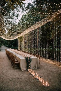 a long table is set up with candles and greenery for an outdoor wedding reception