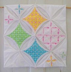 a quilted wall hanging with four different colored squares on it's sides and one has dragonflies in the middle