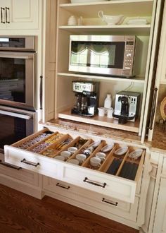 an open drawer in the middle of a kitchen with coffee maker and oven behind it