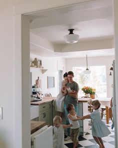 a man and two small children are in the kitchen with their mother holding her baby's hand