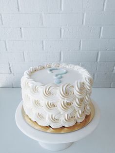 a white frosted cake with a question mark on the top is sitting on a plate