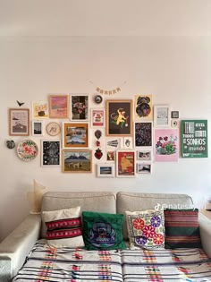 a living room with a couch covered in pillows and pictures on the wall above it