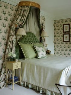 a bedroom with green bedding and floral wallpaper, along with two lamps on either side of the bed