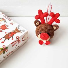 a crocheted reindeer ornament next to a christmas gift box on a white table