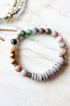 First, at almost 22" in length, this beaded strand can be worn as a necklace and a triple wrap bracelet if you like. Muted greens, grays, beige, gold, desert rose, touches of orange, rust, army green, beige, and more. A great mix of washed out color like a beaten ocean landscape. 6mm to 11mm Pearl, matte 4mm Moss Agate, matte Sunstone, matte 4mm  Jasper stones, and accents of seed beads, and metals. Distressed natural suede loops and coconut button closure make extendable. One-of-a-kind. The ite Jasper Beaded Bracelet Jewelry, Beaded Jasper Jewelry Bracelet, Handmade Agate Beaded Bracelets For Everyday, Earthy Beaded Bracelets With Natural Agate Stones, Earthy Agate Beaded Bracelets With Natural Stones, Adjustable Jasper Beaded Bracelets, Hand Wrapped Agate Round Bead Jewelry, Everyday Handmade Agate Beaded Bracelets, Hand-wrapped Round Agate Bead Jewelry