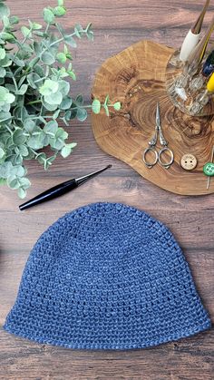 a blue crocheted hat sitting on top of a wooden table next to scissors