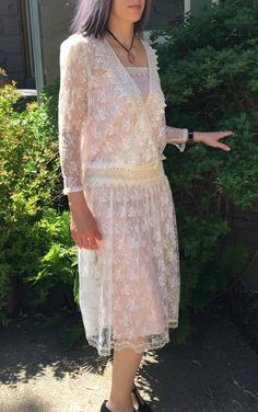 "Lovely Vintage 90's off white lace dress. Sheer see through style. Dare to bare or layer. See that this dress comes with the pink satin lining but we also photographed this with a black slip underneath. (Black slip not included). Measurements for Outer Lace Dress: 14\" Arm 14\" Shoulders 34\" Waist 49\" Length Measurements for Pink Satin Lining: 32\" Bust and Waist 49\" Length" Feminine Scalloped Lace For Wedding, Fitted Lace Dress With Lace Sleeves For Garden Party, Delicate Lace Dress With Scalloped Details, Delicate Scalloped Lace Dress, Spring Cream Lace Dress With Scalloped Edges, Spring Cream Lace Dress With Scalloped Lace, Delicate Lace Dress With Lace Patchwork, Feminine Lace Dress With Lace Bodice For Weddings, Elegant Lace Dress With Scalloped Lace For Wedding Night