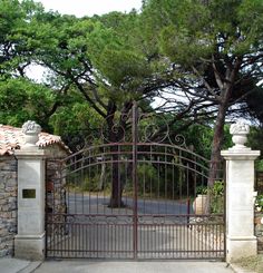 an iron gate with two lions on it and trees in the back ground behind it