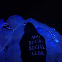 a person standing in front of umbrellas with the words anti social social club on them