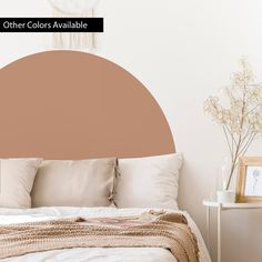 a bed with pillows and blankets on it in a room that is white and has a brown circle over the headboard