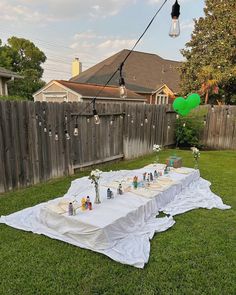 an outdoor table set up in the backyard for a party with balloons and streamers