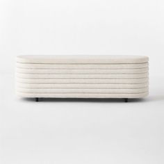 an upholstered white bench with black legs