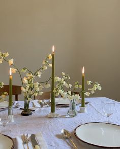 the table is set with candles, plates and flowers in vases on top of it