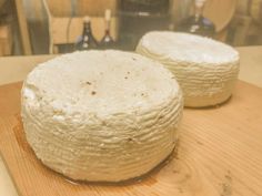 two cheeses sitting on top of a wooden cutting board