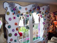 the window is decorated with colorful ornaments and decorations on it's side, along with a christmas tree in the background