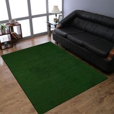 a living room with a black couch and green rug