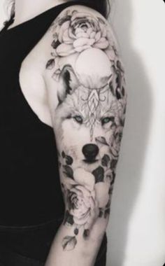 a woman's arm with roses and a wolf tattoo on her left arm,