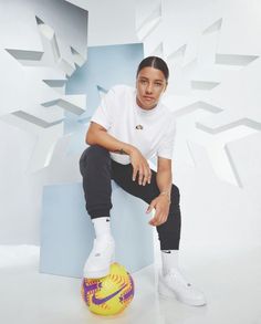 a young man sitting on top of a yellow and purple ball in front of a white background