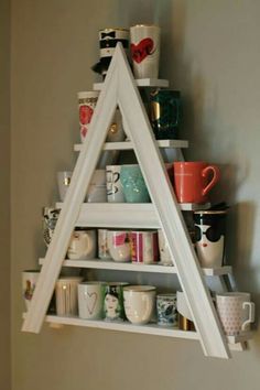 a triangle shaped shelf with cups and mugs on it