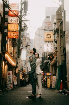 a man and woman standing in the middle of an alleyway with signs above them