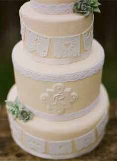 a three tiered wedding cake with white lace and succulents on top