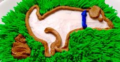 the cake is decorated with green grass and blue icing, including an image of a dog